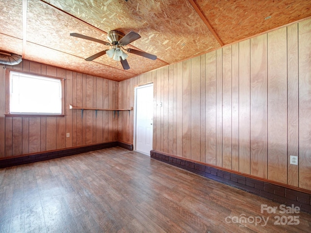 spare room with hardwood / wood-style floors, ceiling fan, and wooden walls