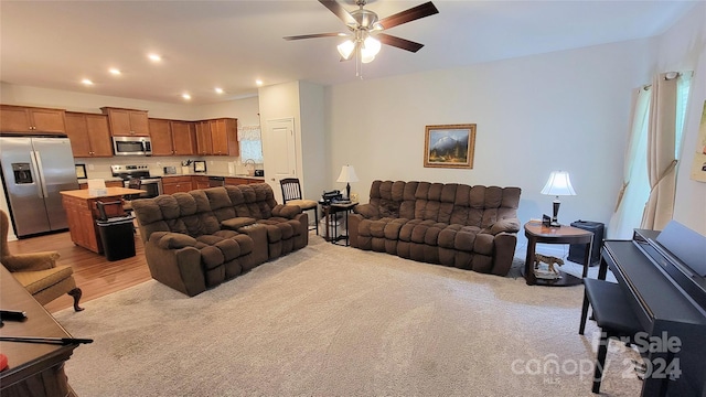 living room featuring a wealth of natural light, light hardwood / wood-style floors, ceiling fan, and sink