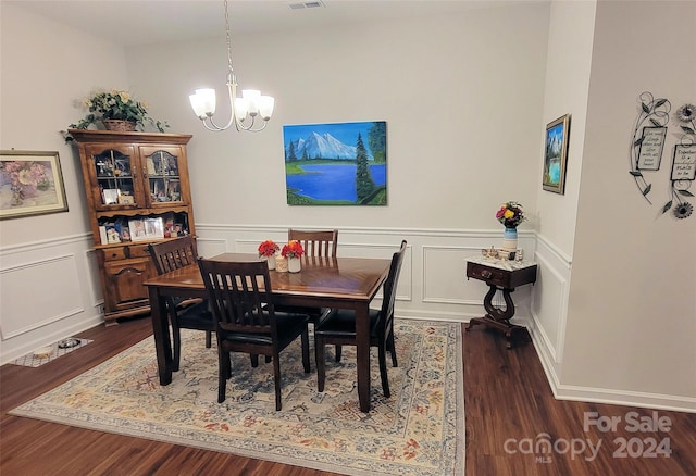 dining space with dark hardwood / wood-style floors and a notable chandelier