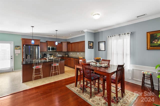 dining space with crown molding and light hardwood / wood-style flooring