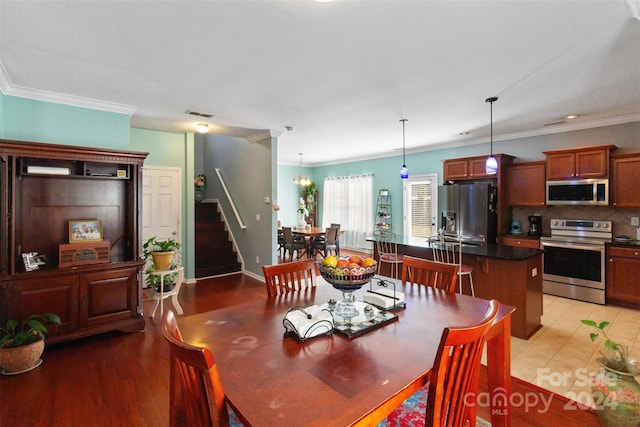 dining room with an inviting chandelier, light hardwood / wood-style floors, and crown molding