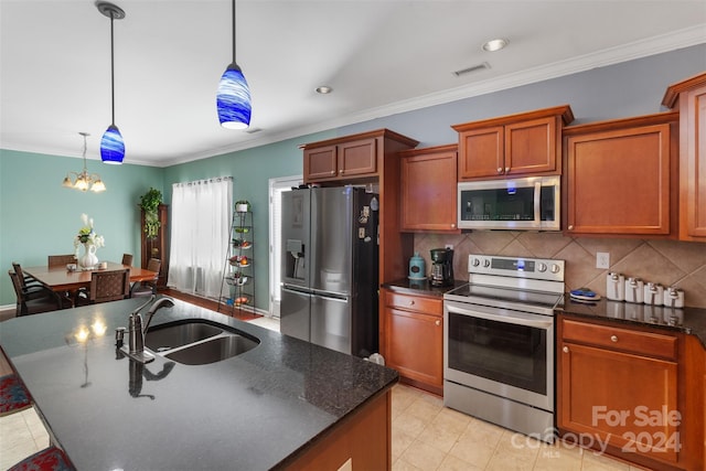 kitchen with an island with sink, pendant lighting, stainless steel appliances, ornamental molding, and sink