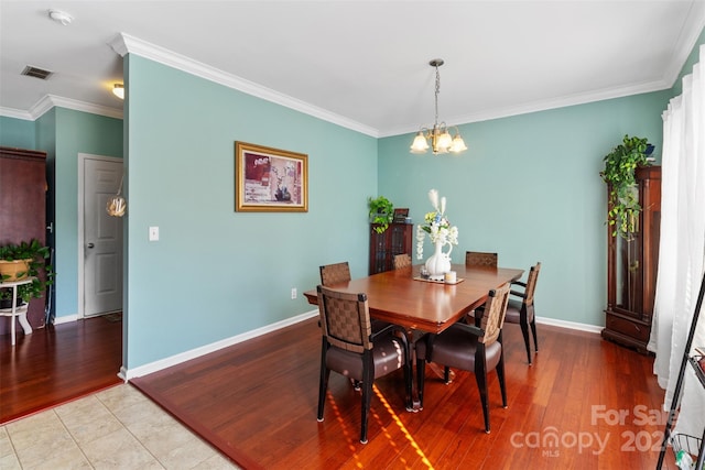 dining area featuring light hardwood / wood-style floors, ornamental molding, and a notable chandelier