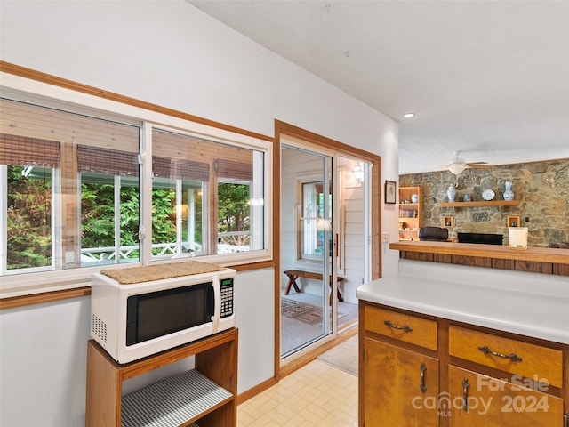 kitchen featuring ceiling fan, a fireplace, and plenty of natural light