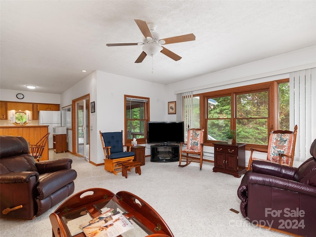 living room with ceiling fan, light carpet, and a textured ceiling