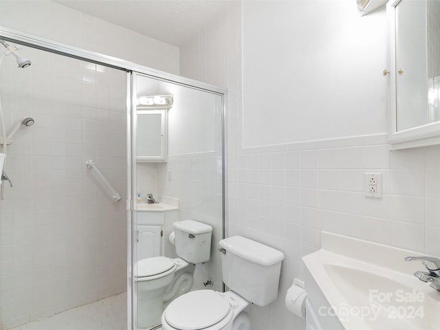 bathroom featuring vanity, toilet, an enclosed shower, and tile walls