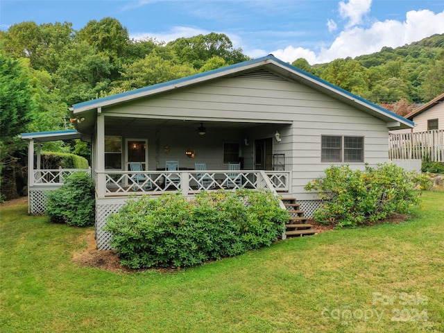 rear view of house with ceiling fan and a yard