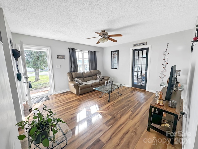 living area featuring baseboards, wood finished floors, a textured ceiling, and ceiling fan