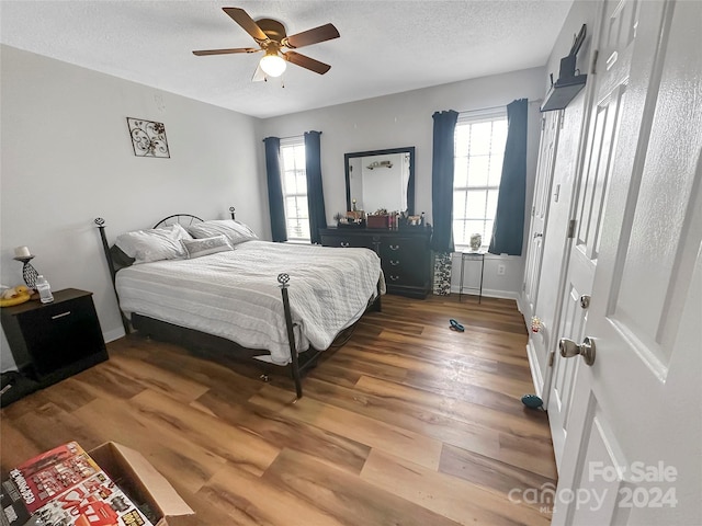 bedroom with wood finished floors, a textured ceiling, and multiple windows