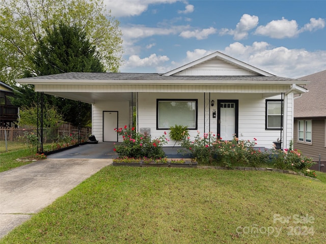 single story home with a porch, a front lawn, and a carport