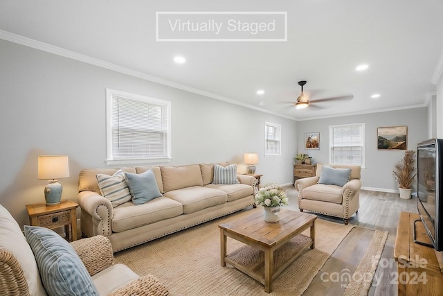 living room with light hardwood / wood-style floors, ornamental molding, and ceiling fan