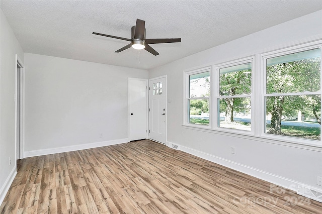 unfurnished room with ceiling fan, a textured ceiling, and light hardwood / wood-style flooring