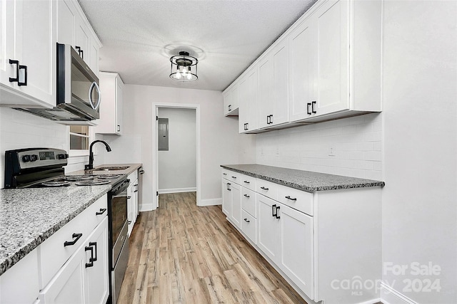 kitchen featuring light hardwood / wood-style floors, tasteful backsplash, sink, stainless steel appliances, and white cabinetry