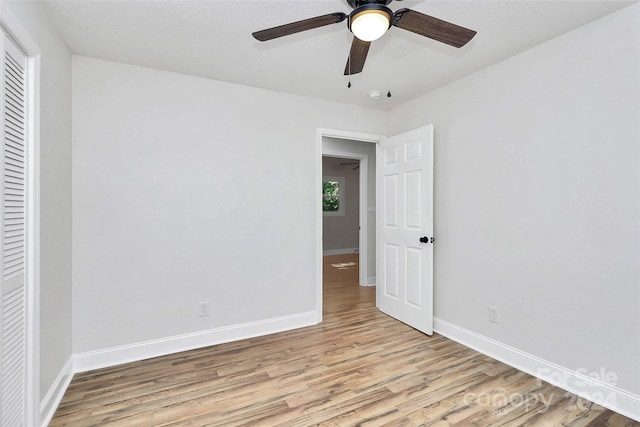 empty room with ceiling fan, a textured ceiling, and light wood-type flooring