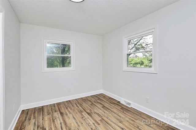 empty room with hardwood / wood-style floors and a textured ceiling