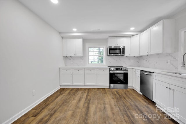 kitchen with backsplash, sink, white cabinets, and appliances with stainless steel finishes