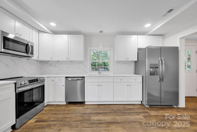 kitchen with white cabinetry, hanging light fixtures, and appliances with stainless steel finishes