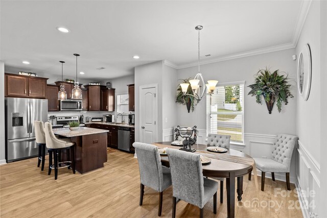 dining room featuring crown molding, sink, light hardwood / wood-style flooring, and a notable chandelier