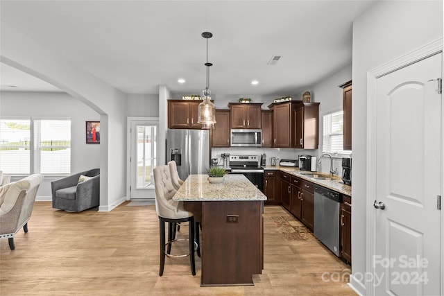 kitchen featuring hanging light fixtures, a kitchen island, stainless steel appliances, and a wealth of natural light