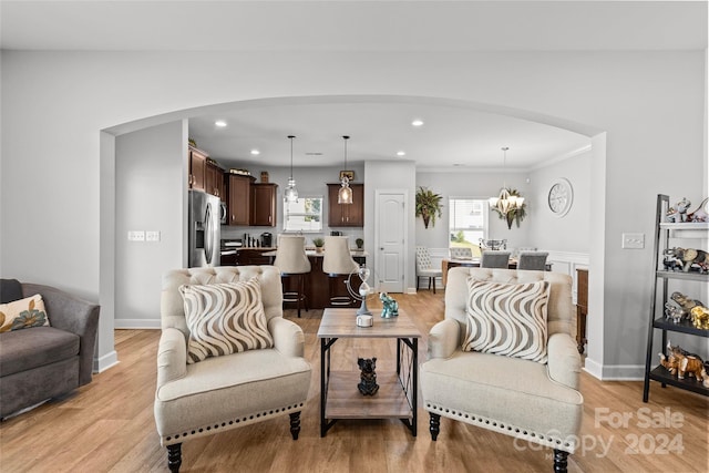 living room featuring light wood-type flooring, a chandelier, and crown molding