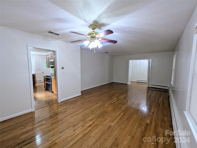 unfurnished room featuring baseboard heating, dark wood-type flooring, and ceiling fan