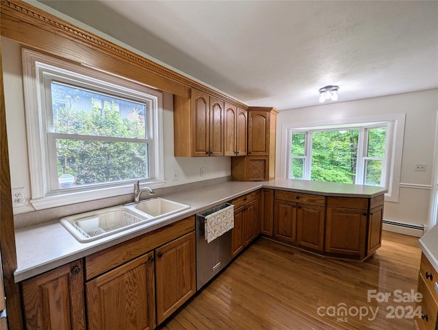 kitchen with a baseboard heating unit, kitchen peninsula, sink, stainless steel dishwasher, and light hardwood / wood-style floors