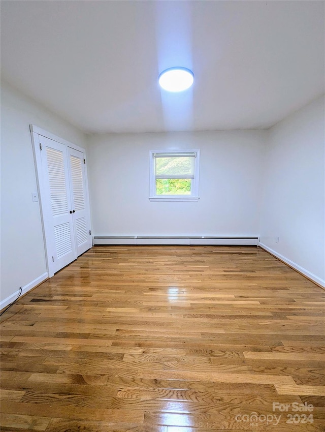 interior space featuring a closet, a baseboard radiator, and light wood-type flooring