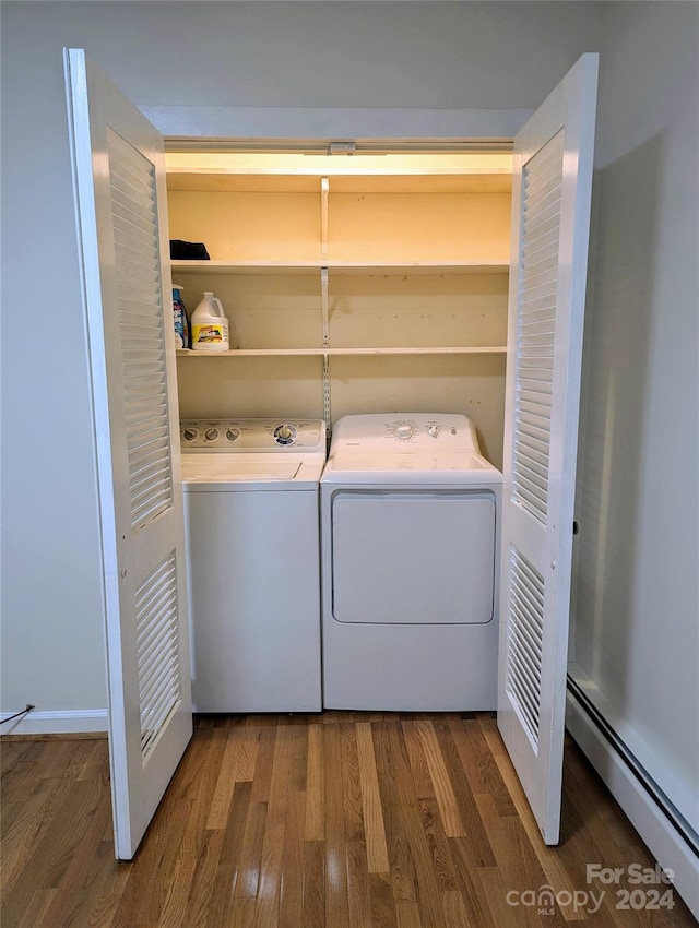 laundry area with a baseboard radiator, hardwood / wood-style floors, and washing machine and clothes dryer