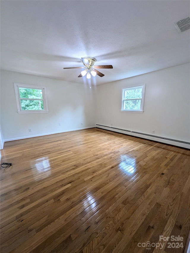 empty room featuring baseboard heating, dark wood-type flooring, and ceiling fan