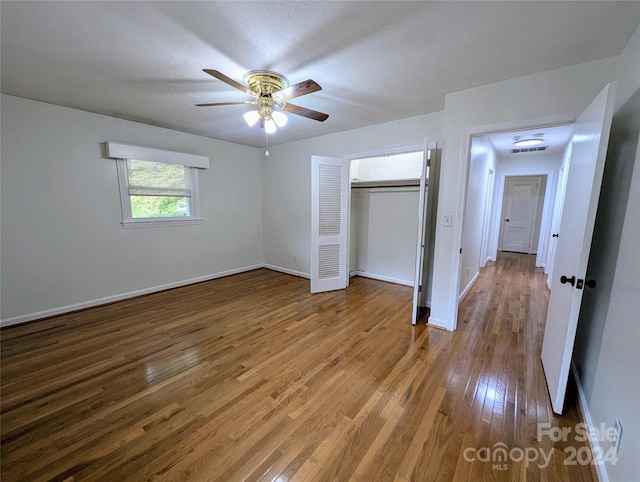 unfurnished bedroom with a closet, ceiling fan, hardwood / wood-style flooring, and a textured ceiling