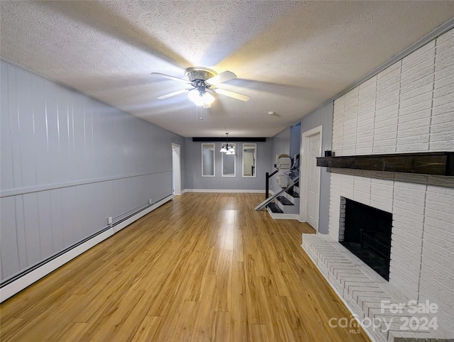 unfurnished living room featuring a baseboard radiator, a brick fireplace, a textured ceiling, and light wood-type flooring