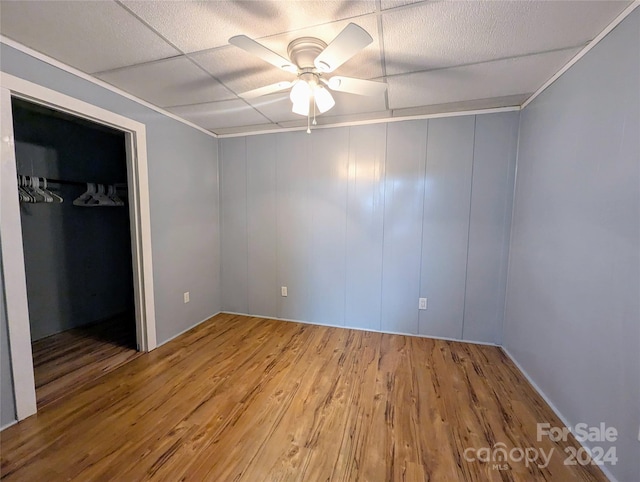 unfurnished bedroom with a closet, ceiling fan, wood-type flooring, and a drop ceiling