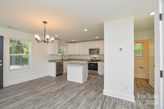 kitchen with a wealth of natural light, a kitchen island, appliances with stainless steel finishes, and white cabinetry