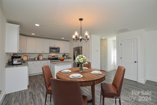 dining area featuring dark wood-type flooring and an inviting chandelier