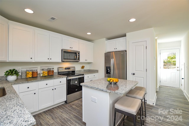 kitchen featuring white cabinetry, light stone counters, stainless steel appliances, and a kitchen island