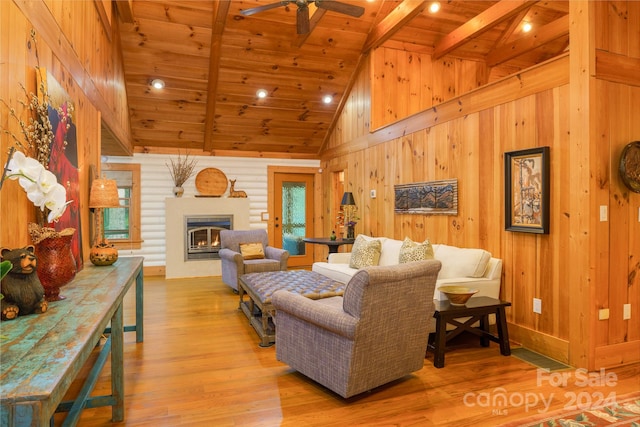 living room featuring beam ceiling, light hardwood / wood-style floors, ceiling fan, and wooden ceiling