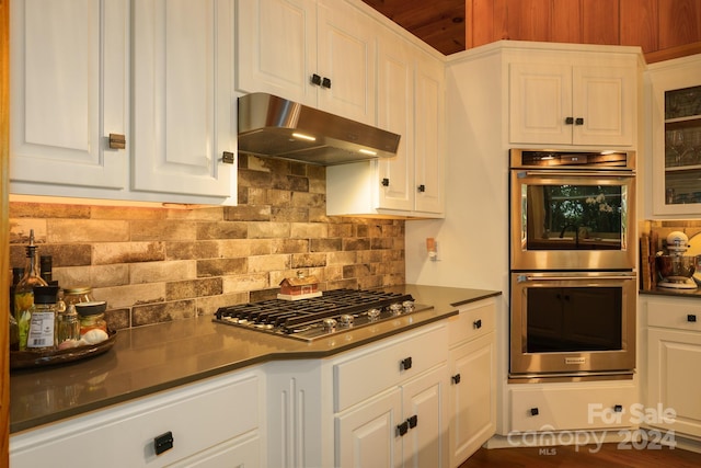 kitchen with stainless steel appliances, white cabinetry, hardwood / wood-style floors, and backsplash