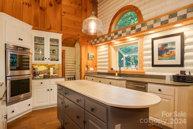 kitchen featuring appliances with stainless steel finishes, white cabinets, pendant lighting, a center island, and sink