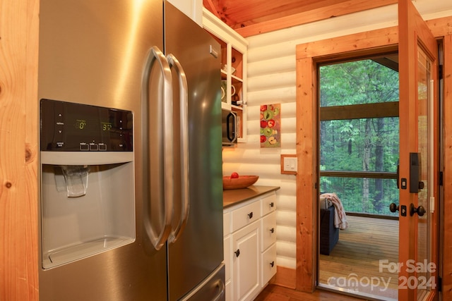 kitchen with wood ceiling, white cabinetry, stainless steel refrigerator with ice dispenser, hardwood / wood-style floors, and rustic walls