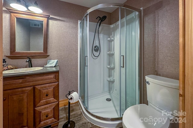 bathroom with walk in shower, vanity, toilet, and wood-type flooring