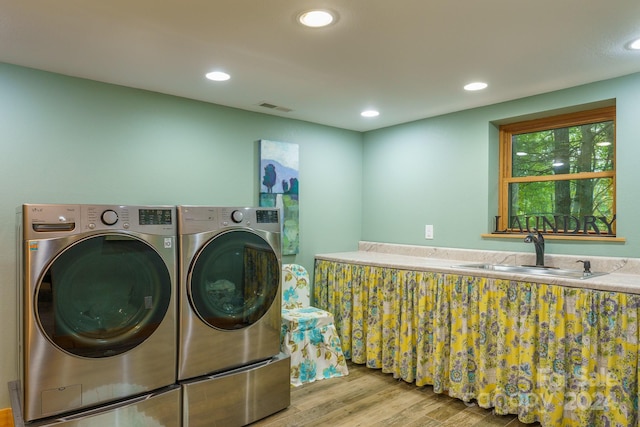 laundry room featuring wood-type flooring, sink, and washer and dryer