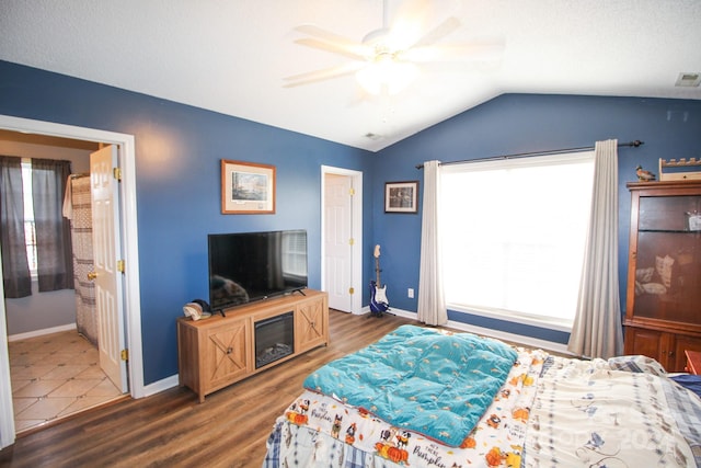 bedroom featuring ceiling fan, dark hardwood / wood-style floors, vaulted ceiling, and multiple windows