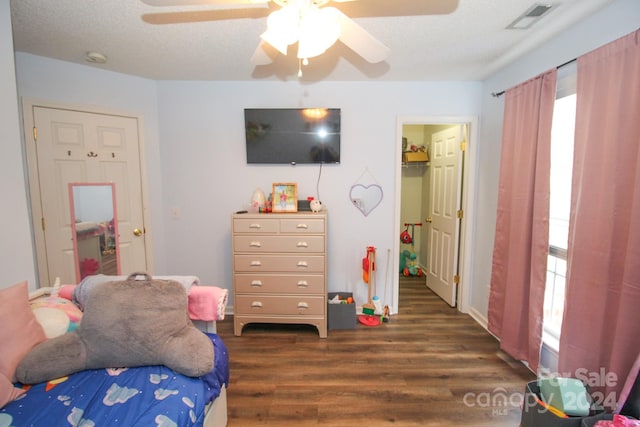 bedroom with multiple windows, a textured ceiling, dark wood-type flooring, and ceiling fan