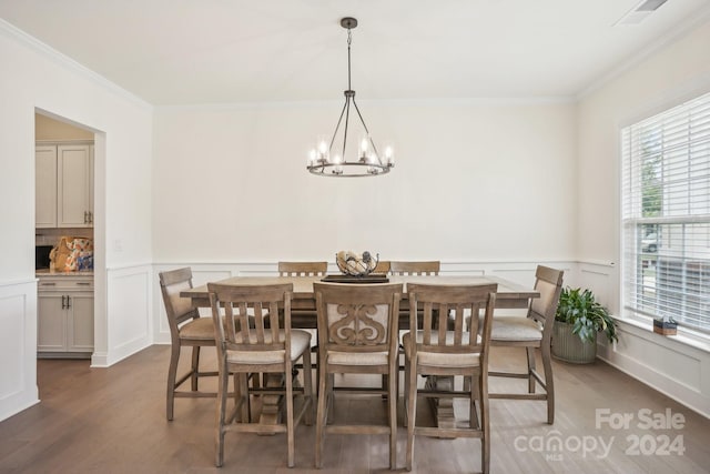 dining space with ornamental molding, a notable chandelier, and dark hardwood / wood-style flooring