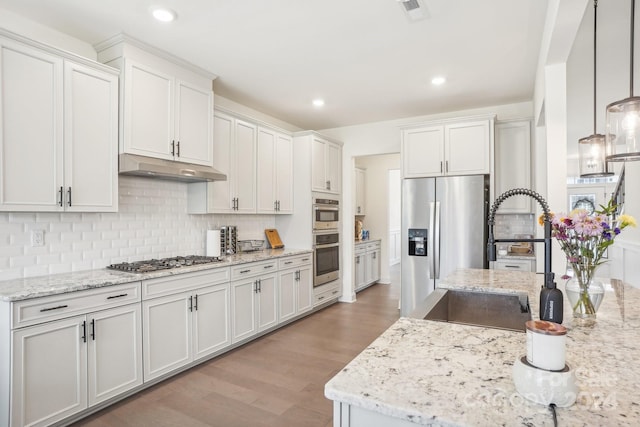 kitchen with appliances with stainless steel finishes, hanging light fixtures, light hardwood / wood-style floors, and white cabinetry