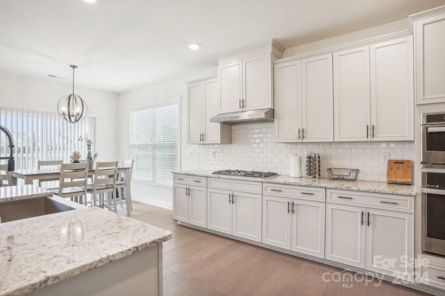 kitchen featuring decorative backsplash, white cabinetry, light hardwood / wood-style floors, and decorative light fixtures