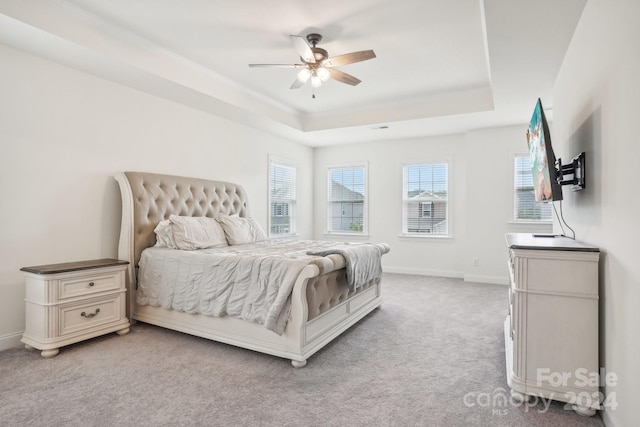 bedroom featuring a raised ceiling, carpet flooring, and ceiling fan