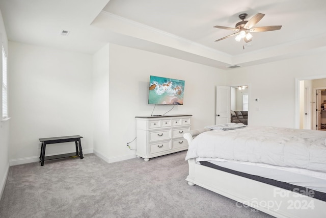 bedroom featuring light carpet, a tray ceiling, and ceiling fan