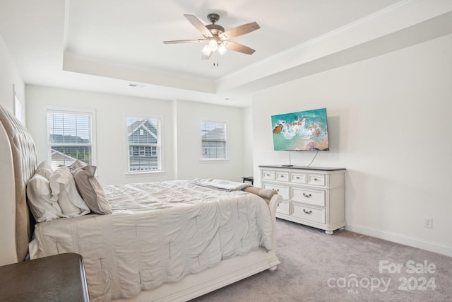 bedroom with ceiling fan, light colored carpet, and a tray ceiling