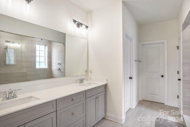 bathroom with hardwood / wood-style flooring, vanity, and tiled shower